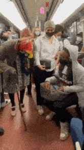a group of people wearing face masks are riding a subway train .