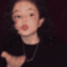 a blurry picture of a woman wearing a black shirt and necklace .