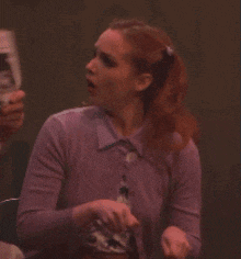 a woman in a purple shirt and tie is holding a newspaper
