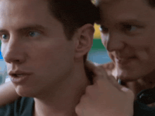 a close up of two men 's faces with one looking at the other