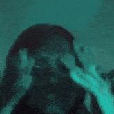 a close up of a woman holding her head with her hands .
