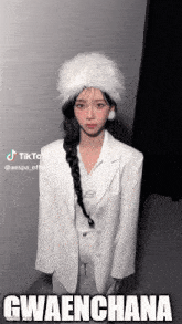 a woman wearing a white jacket and a white hat is standing in front of a wall .