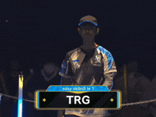 a man wearing a shirt that says trg stands in the dark