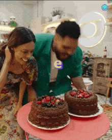 a man and a woman are standing next to two cakes on a pink table