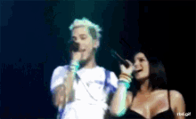 a blurry picture of a man and a woman singing on a stage with rbd.gif written on the bottom