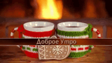 two cups of tea and a gingerbread cookie on a table with a fireplace in the background