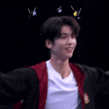 a young man wearing a red jacket and a white t-shirt is smiling while standing in front of a microphone .