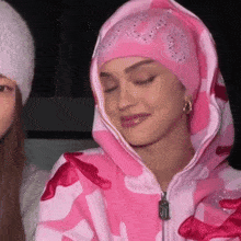 a woman is wearing a pink hoodie and a pink hat .