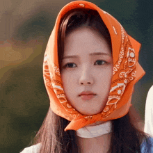a woman wearing an orange bandana on her head with the letter a on it
