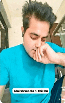 a man wearing a blue shirt is covering his nose with his hand .