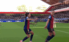 two female soccer players celebrate a goal on a field