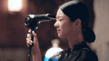 a woman holds a hair dryer to her eye