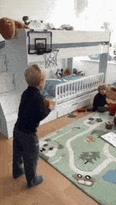 two young boys playing in a bedroom with a basketball hoop