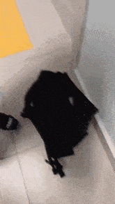 a black backpack is laying on a tiled floor
