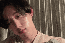 a close up of a young man 's face with a white shirt on