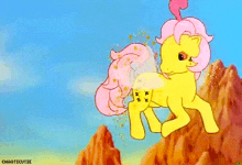 a yellow pony with a pink mane and tail is standing on a mountain