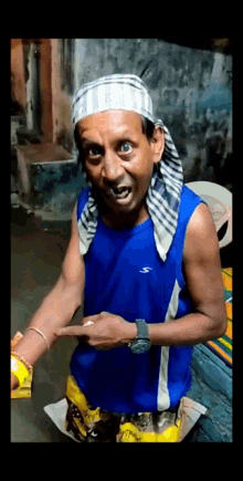 a man wearing a head scarf and a blue shirt with the word slazenger on it