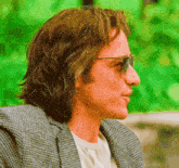 a man with long hair is wearing sunglasses and a plaid jacket .
