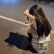 a girl in a plaid skirt is kneeling on the ground