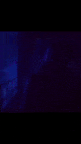 a man with a beard and a bandage on his head is standing in front of a purple background and smiling .