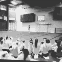 a group of people are sitting in a gym watching a basketball game