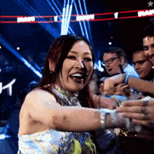 a woman stands in front of a crowd with a sign in the background that says ' wwe '