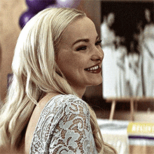 a close up of a woman wearing a lace top smiling .
