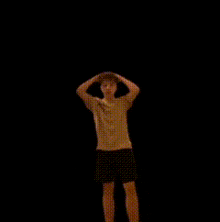 a person in a white shirt and black shorts is standing in the dark