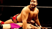 a shirtless wrestler is wrestling another wrestler in a ring .