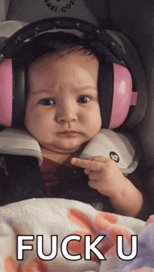 a baby wearing pink ear muffs is pointing at the camera with the words fuck u below it