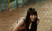 a woman with long black hair is kneeling down on the ground .