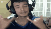 a man wearing headphones and a blue shirt is making a funny face .