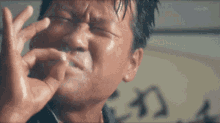 a man is making a funny face with his hands while smoking a cigarette .