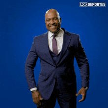 a man in a suit and tie stands in front of a fox deportes sign