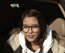 a woman wearing glasses is sitting in a car with a colorful sign above her head that says ' a ' on it