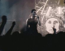 a man singing into a microphone in front of a drum kit