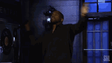 a man in a black shirt is standing in front of a snl sign