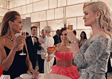 a woman in a pink dress holds a martini while talking to two other women