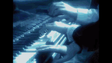 a person is playing a piano with a blue light shining on the keys