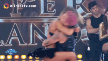 a man and woman are hugging in front of a sign that says " eltrecetv.com "