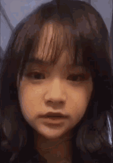 a close up of a young girl 's face with bangs making a funny face .