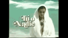 a woman is standing on a beach wearing a white robe and sunglasses .