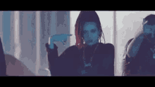 a woman with red hair and dreadlocks is dancing in a dark room with a group of people .