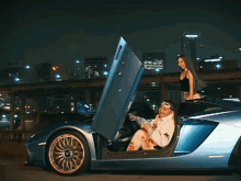 a man is sitting in a blue sports car with his door open