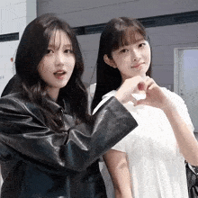 two girls are posing for a picture and one is making a heart with her hands