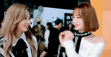 two girls are standing next to each other and smiling at each other