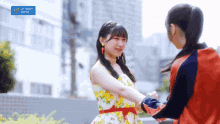 two girls are shaking hands in front of a sign that says " upfront works "
