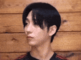a close up of a person 's face with a wooden wall in the background
