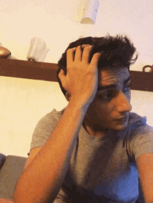 a man in a gray shirt is holding his head