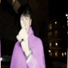 a man in a purple hoodie is giving a middle finger .